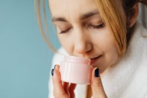 Een vrouw die geniet van de geur van een natuurlijke huidverzorging crème in haar handen.